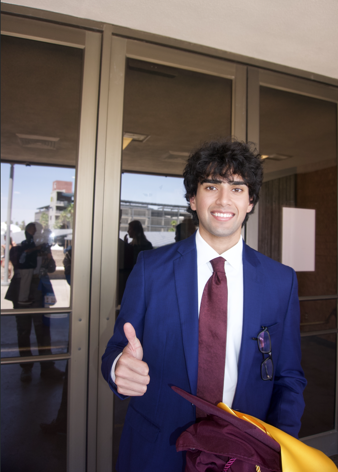 Yash smiling and giving a thumbs up in his ASU graduation gown.
